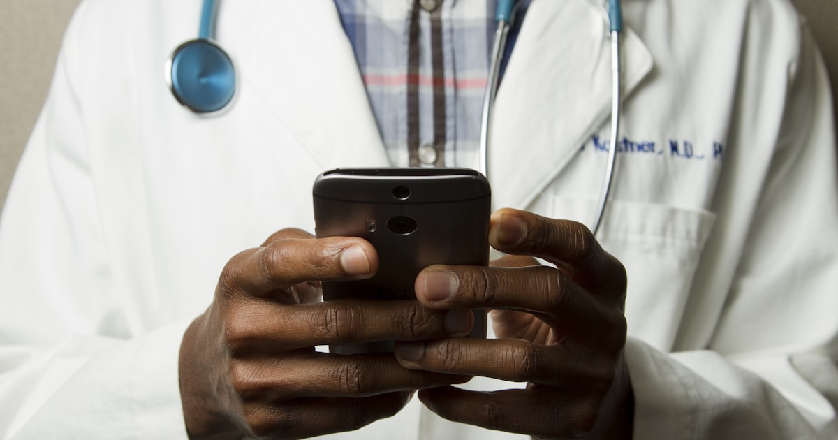 Healthcare professional in a white coat reviews information on a mobile device